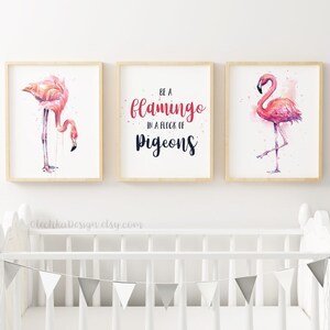 May include: Three framed watercolor prints featuring pink flamingos. The center print has the text "Be a flamingo in a flock of pigeons".