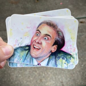 Op de afbeelding: Een aquarel schilderij van een man met een verraste uitdrukking. Het schilderij is op een witte achtergrond met roze en gele aquarel spatten.