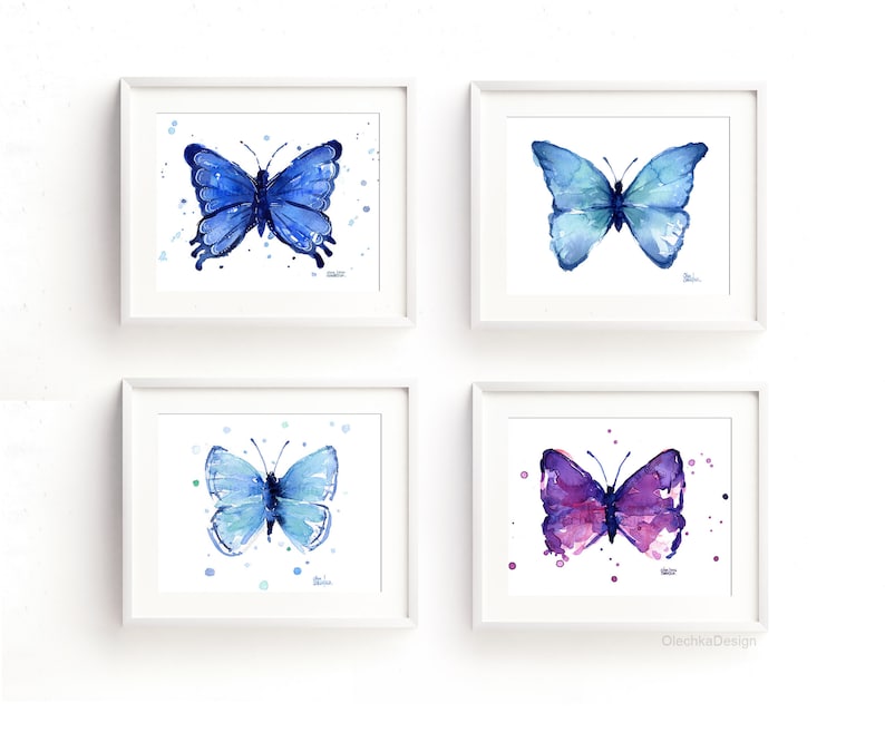 May include: Set of four watercolor paintings of butterflies in shades of blue and purple. Each butterfly is surrounded by small white dots on a white background. The paintings are framed in white frames.