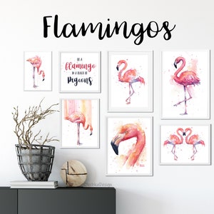 May include: A set of 7 framed watercolor paintings featuring pink flamingos. The paintings are in white frames and are arranged on a white wall. One of the paintings has the text "Be a flamingo in a flock of pigeons".