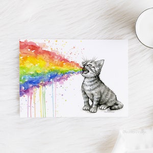K&ouml;nnte beinhalten: Aquarellmalerei eines grauen K&auml;tzchens, aus dessen Maul ein Regenbogen kommt. Der Regenbogen besteht aus Aquarellfarbe und hat einen tropfenden Effekt.