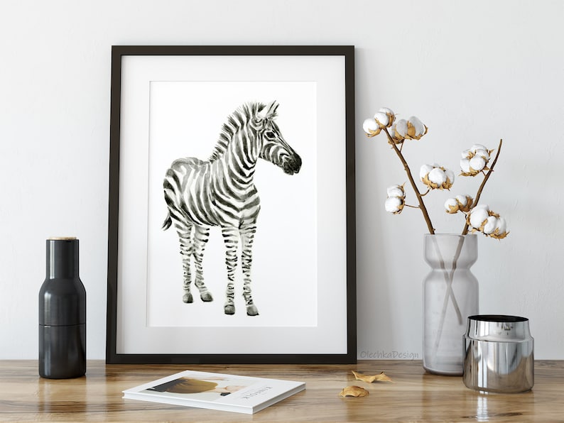 May include: Black and white watercolor painting of a zebra foal standing on a white background. The zebra has black stripes on a white background. The painting is framed in a black frame.
