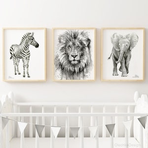 May include: Three black and white animal illustrations in wooden frames. The illustrations are of a zebra, a lion, and an elephant. The frames are hanging on a white wall above a white crib with a gray and white bunting.