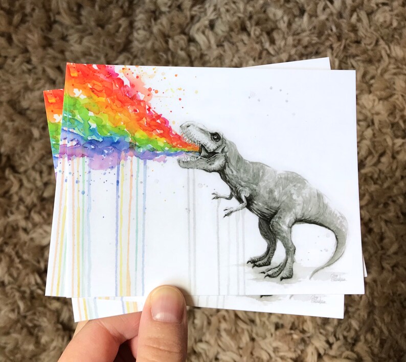 May include: A watercolor painting of a dinosaur breathing out a rainbow. The dinosaur is gray and has a white background. The rainbow is colorful and has a watercolor effect.