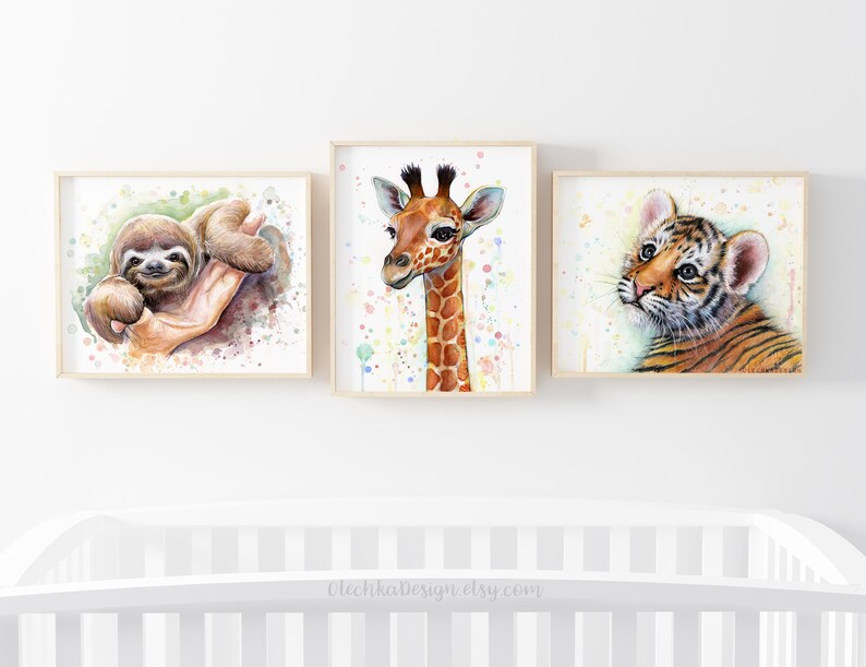 May include: Three watercolor paintings of baby animals in frames. The first painting features a sloth with a green background. The second painting features a giraffe with a white background and colorful dots. The third painting features a tiger with a white background and colorful dots.