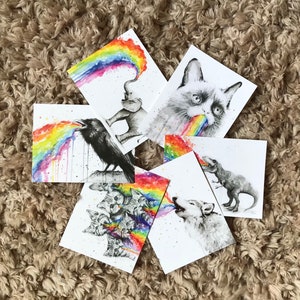 May include: Set of six illustrated cards featuring various animals blowing rainbows. The animals include a raven, a cat, a wolf, a dinosaur, an elephant, and a group of kittens.