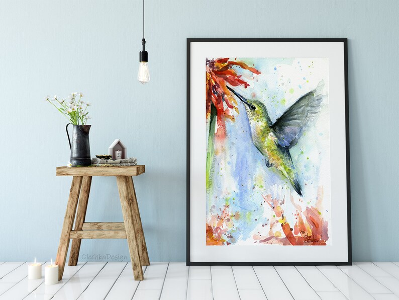 May include: Watercolor painting of a hummingbird in flight, with its beak extended towards a red flower. The background is a soft blue with splashes of green and orange.