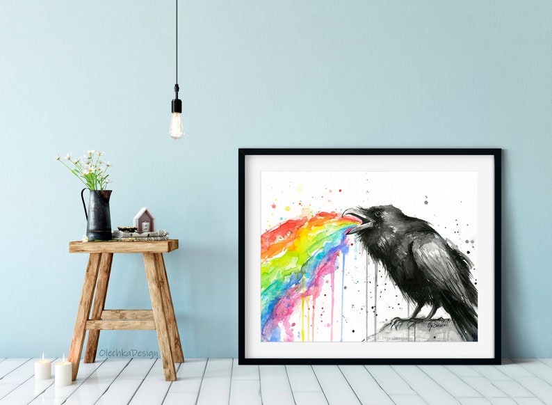 May include: A black and white watercolor painting of a raven with a rainbow coming out of its mouth. The rainbow is made up of different colors, including red, orange, yellow, green, blue, indigo, and violet. The raven is perched on a rock and has a serious expression on its face.