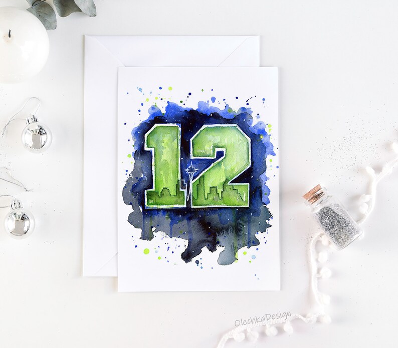 May include: Watercolor painting of the number 12 in green and blue with a cityscape silhouette inside the number. The background is a dark blue with white splatters. The text "OlechkaDesign" is in the bottom right corner.