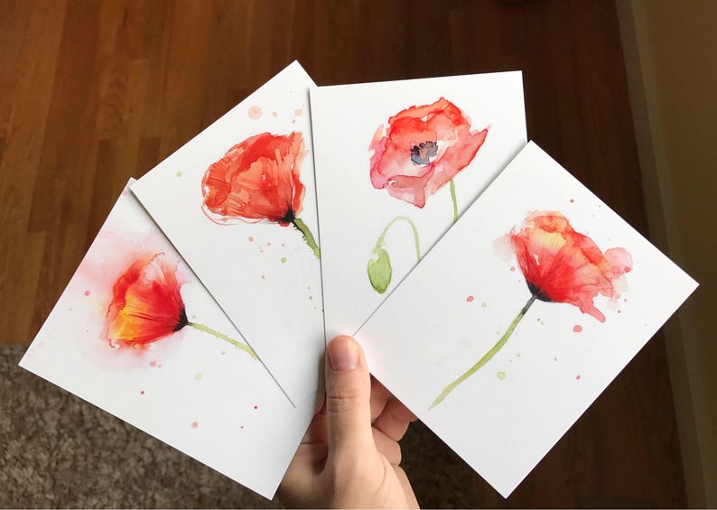May include: Four watercolor paintings of red poppies on white card stock. Each painting features a single poppy with a green stem and leaves. The poppies are painted in shades of red, orange, and yellow.