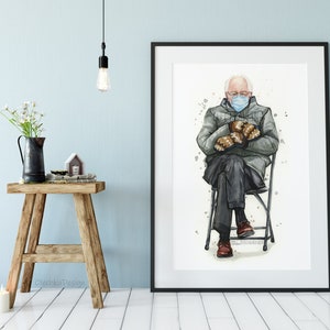 May include: Watercolor painting of a man wearing a blue face mask and a gray jacket, sitting on a folding chair with his hands in his lap. He is wearing brown gloves and brown shoes. The painting is framed in a white frame.