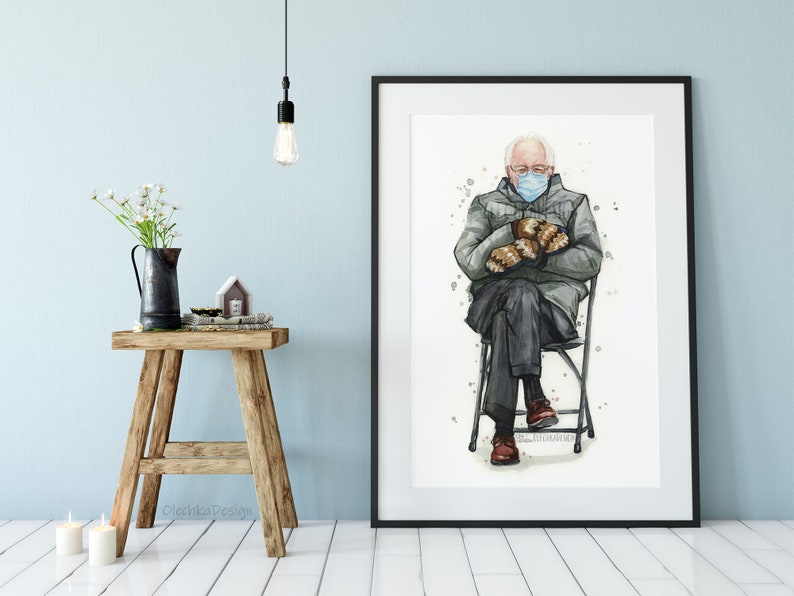 May include: Watercolor painting of a man wearing a blue face mask and a gray jacket, sitting on a folding chair with his hands in his lap. He is wearing brown gloves and brown shoes. The painting is framed in a white frame.