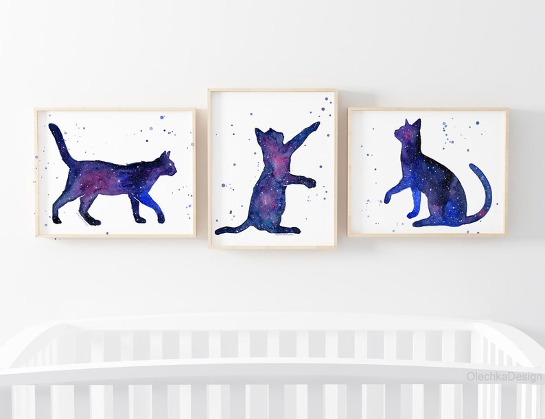 May include: Three watercolor paintings of galaxy cats. Each cat is a different pose, with a blue and purple galaxy pattern.