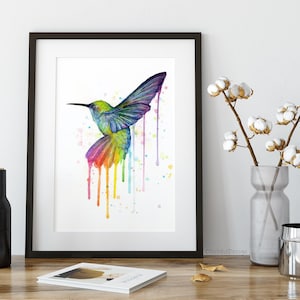 May include: A watercolor painting of a colorful hummingbird with rainbow-colored drips and splatters on a white background.