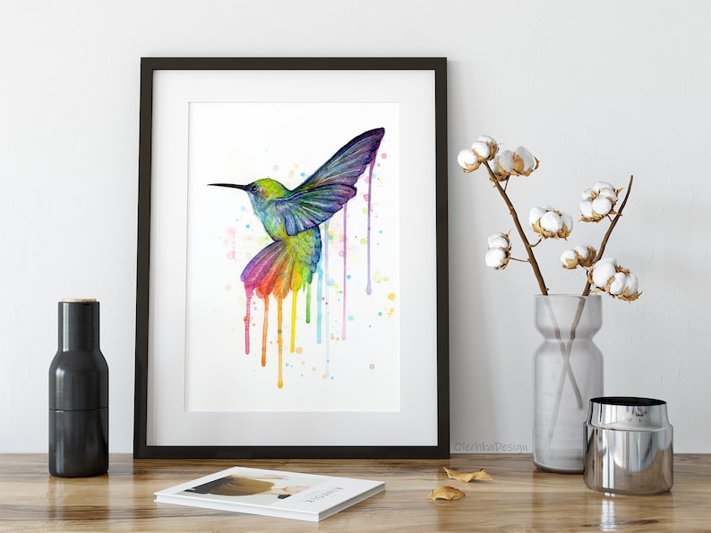 May include: A watercolor painting of a colorful hummingbird with rainbow-colored drips and splatters on a white background.