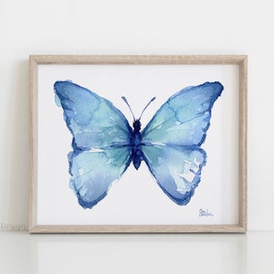 May include: A watercolor painting of a blue butterfly with its wings spread open. The butterfly is painted in shades of blue and green, and the background is white.