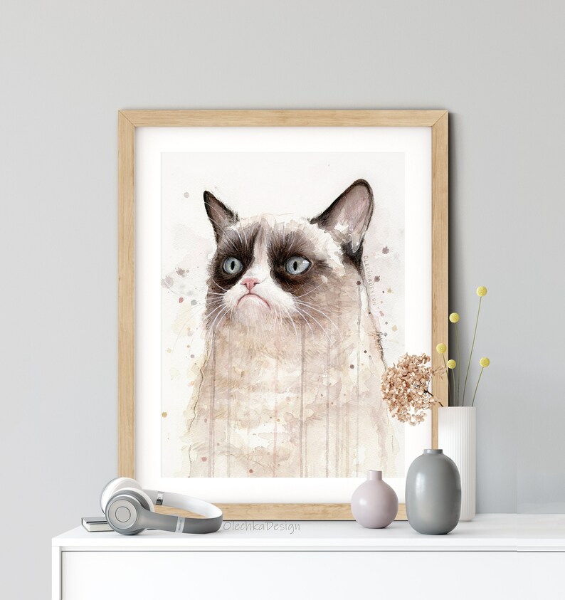 May include: A watercolor painting of a grumpy cat with brown and white fur. The cat has a serious expression and is looking to the left. The background is a light brown with watercolor splatters.