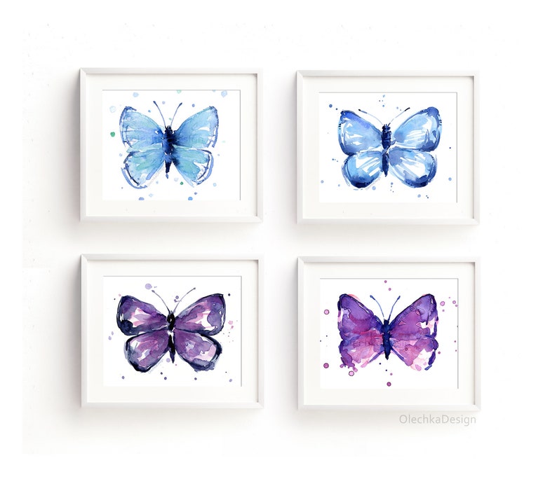 May include: Four watercolor paintings of butterflies in white frames. The butterflies are blue, purple, and pink. The paintings are arranged in a grid pattern on a white wall.