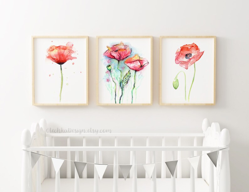 May include: Three framed watercolor paintings of red poppies with green stems and leaves. The paintings are displayed on a white wall above a white crib with a gray bunting.