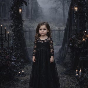 Puede incluir: Una ni&ntilde;a con un vestido negro de encaje se encuentra en un entorno g&oacute;tico al aire libre. El vestido tiene mangas largas y una falda de tul. El fondo incluye un arco oscuro, velas y una iglesia borrosa.
