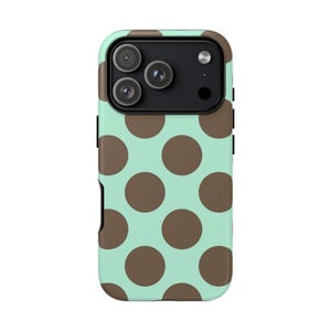 May include: A smartphone case featuring a repeating pattern of large, solid brown circles set against a light mint green background. The case includes a rectangular black camera module cutout at the top, designed to accommodate three lenses and a flash.