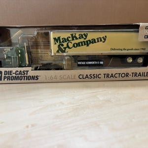 May include: A 1:64 scale die-cast metal replica of a Kenworth K-100 tractor-trailer in its original packaging. The trailer is cream-colored with green text reading Mackay & Company and Delivering the goods since 1968. The box is labeled Die-Cast Promotions.