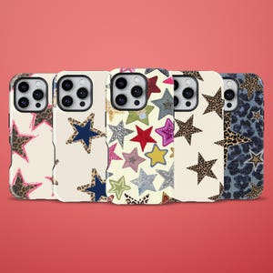 Può includere: Cinque cover per smartphone disposte in fila, ognuna caratterizzata da un design unico con stelle. Le cover presentano varie texture e colori, tra cui stampa leopardata, blu navy tinta unita e motivi a stelle multicolori su sfondi crema e blu.