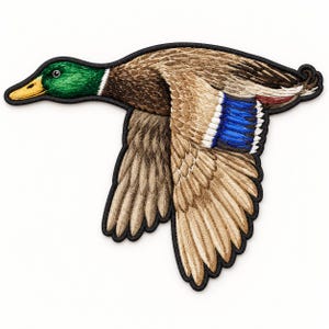 May include: An embroidered iron-on patch shaped like a mallard duck in flight. The duck features a vibrant green head, a yellow beak, and brown feathers with a distinct blue patch on the wing, all outlined with a thick black border.