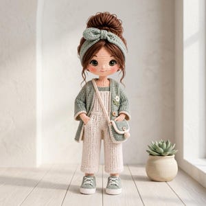 May include: A handcrafted crochet doll with brown hair styled in a high bun, wearing a sage green headband with a bow, a matching sage green cardigan, cream-colored overalls, and a small crossbody bag. The doll wears light green sneakers.
