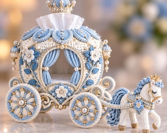 May include: A crocheted carriage and horse set in white and light blue yarn. The carriage features a crown topper, floral accents, and pearl beads, with a white tissue emerging from the top. The horse has a blue mane, tail, and a crown.