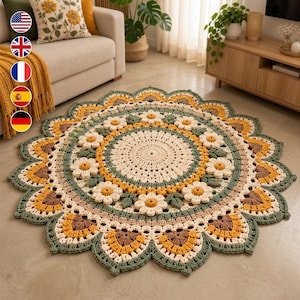 Puede incluir: Una alfombra redonda de ganchillo con un patrón circular central de color crema, rodeado por un anillo de margaritas blancas tridimensionales con centros amarillos, intercaladas con hojas verdes y un borde festoneado en amarillo, marrón y verde.