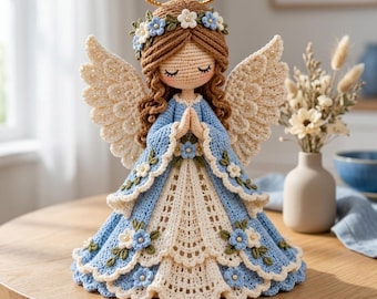 May include: A crocheted angel figurine with brown yarn hair, a gold halo, and large textured wings. The angel wears a layered blue and white dress adorned with small blue and white floral appliques and green leaves, with hands clasped in prayer.