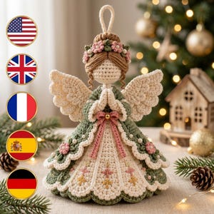 May include: A crocheted angel figurine with light brown hair, a floral crown, and cream-colored wings. The angel wears a layered green and cream dress adorned with small pink flowers, white pearls, and a pink ribbon bow at the waist.