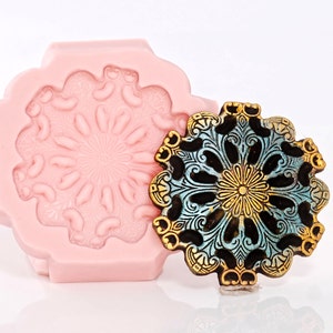 May include: A pink silicone mould with a detailed floral design, and a matching metal ornament with a blue and gold finish.