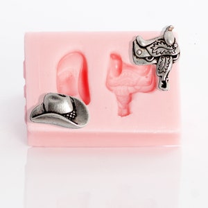 May include: A pink silicone mold with two cavities. One cavity is shaped like a cowboy hat and the other is shaped like a saddle.