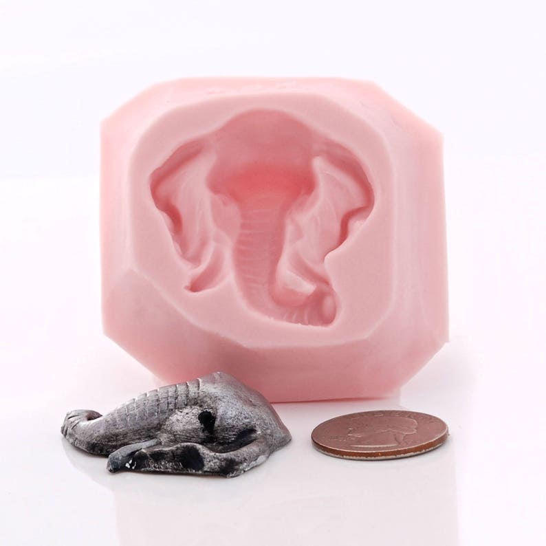 Puede incluir: Molde de silicona rosa para hacer una peque&ntilde;a figura de elefante. El molde tiene forma de diamante y presenta un dise&ntilde;o de elefante detallado. Se muestra una peque&ntilde;a figura de elefante gris junto al molde.