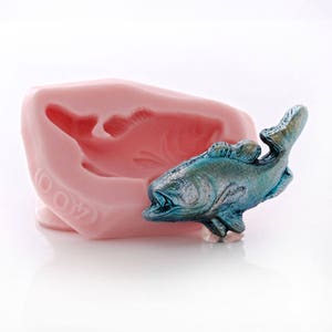 May include: A pink silicone mold of a fish with a blue and green fish figurine next to it. The mold has the number 007 embossed on it.