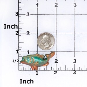 May include: A small, green and gold metal fish figurine. The fish is about 1.5 inches long and has a detailed design.
