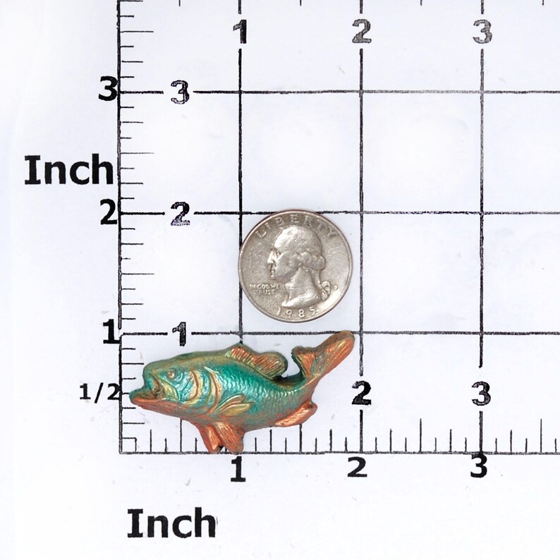 May include: A small, green and gold metal fish figurine. The fish is about 1.5 inches long and has a detailed design.