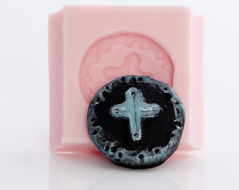May include: A silicone mold for making a round, black, resin pendant with a silver cross design.