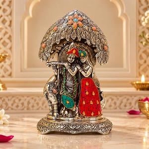 May include: A silver-toned metal figurine depicting two figures standing under a tree canopy. The figures are adorned with colorful inlaid stones in shades of red, green, and turquoise. The base is circular and features intricate embossed patterns.