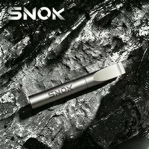 May include: A cylindrical metallic gray device with a tapered mouthpiece and the word SNOK printed on the body. The object features a smooth, matte finish and is positioned diagonally, displaying the brand name SNOK at the top left corner.