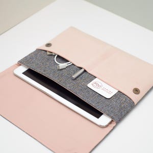 May include: A pink and grey fabric laptop sleeve with a zipped pocket and a small pocket for accessories. The sleeve has a label that says "KM Sewing Designs".