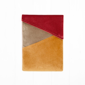 Puede incluir: Un bolso de mano rectangular de terciopelo con un diseño geométrico de bloques de color. La sección superior es de color rojo intenso, la del medio es de color topo apagado y la inferior es de color amarillo mostaza cálido. Las costuras están cosidas con hilo claro.