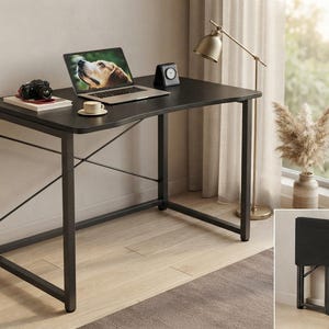 May include: A black rectangular desk with a metal frame and X-shaped support bars on the sides. The desk surface is flat and dark, shown in an assembled state and also in a folded, compact position in a small inset image at the bottom right.