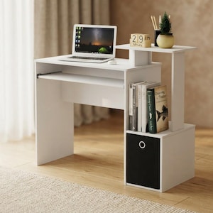 May include: A white computer desk featuring a laptop on the main surface, a sliding keyboard tray, a raised shelf with a small plant and calendar, vertical book storage, and a lower cubby containing a black fabric storage bin.