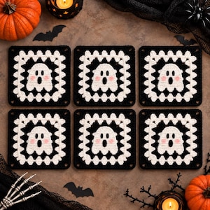 May include: Six square crochet coasters featuring a white ghost motif with black eyes and mouth and pink cheeks, centered on a black background with a white scalloped border. Each coaster is identical in design, showcasing a detailed yarn texture.
