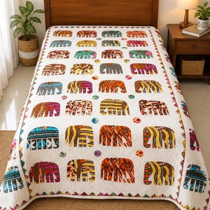 Op de afbeelding: Een witte quilt met een herhalend patroon van gestileerde olifanten in diverse kleuren en texturen, waaronder strepen, bloemenprints en geometrische ontwerpen. Kleine kleurrijke cirkels zijn verspreid tussen de olifanten en een rand omlijst de quilt.