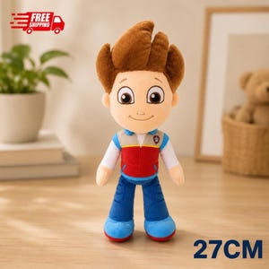 Puede incluir: Un peluche de 27 cm de un personaje de dibujos animados con cabello castaño, ojos grandes de color marrón y una sonrisa amable. El personaje viste una camisa blanca de manga larga, un chaleco rojo y gris con un emblema de huella y pantalones azules.
