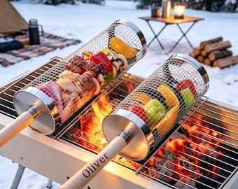 May include: Two cylindrical stainless steel wire mesh grilling baskets with light wood handles, one engraved with the name Oliver, containing assorted vegetables and meat, positioned over a charcoal grill with glowing embers.